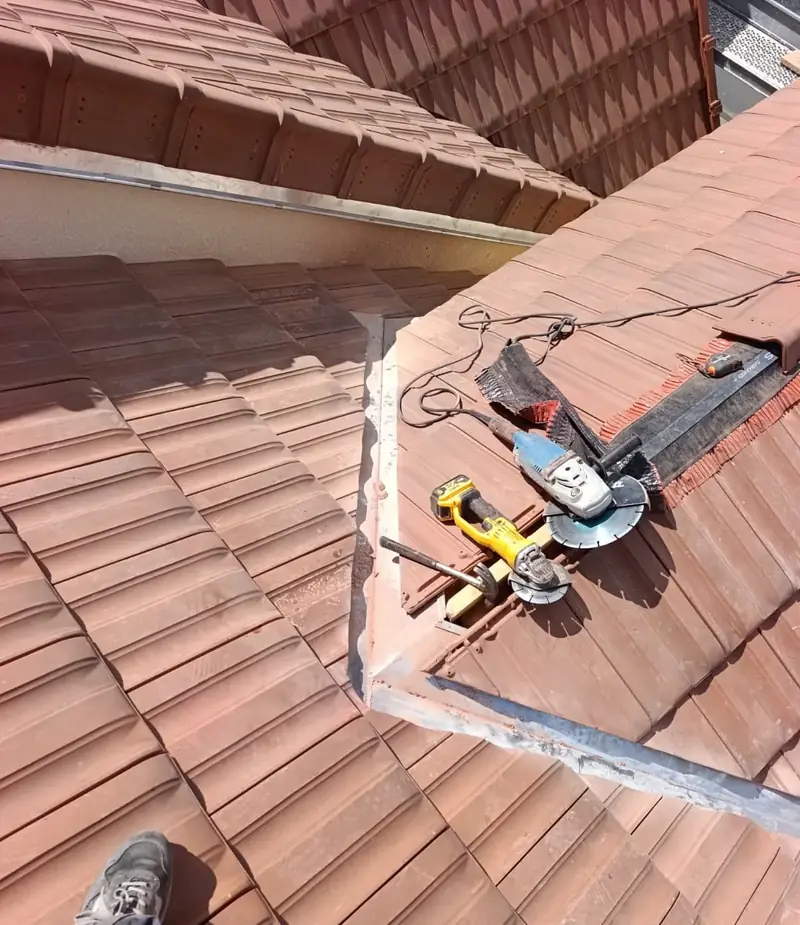 Noue de lucarne en zinc en cours de pose, meuleuses et marteau posés sur les tuiles, Champigny-sur-Marne (94)