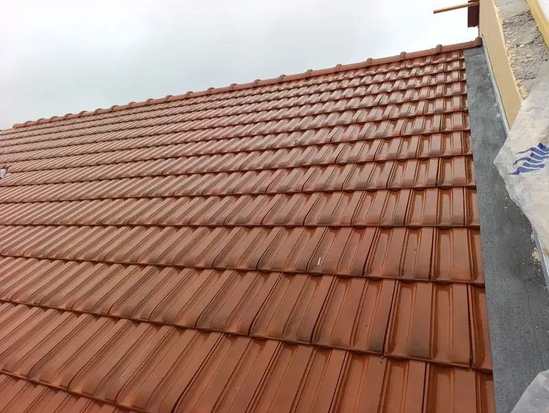 Tuiles mécaniques neuves raccordées à un mur par une bande d'étanchéité et un solin en zinc, Champigny-sur-Marne (94)