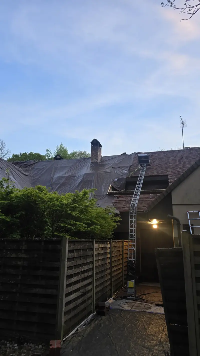 Toiture recouverte d'une bâche de protection, échelle contre la façade, Chevreuse (78)