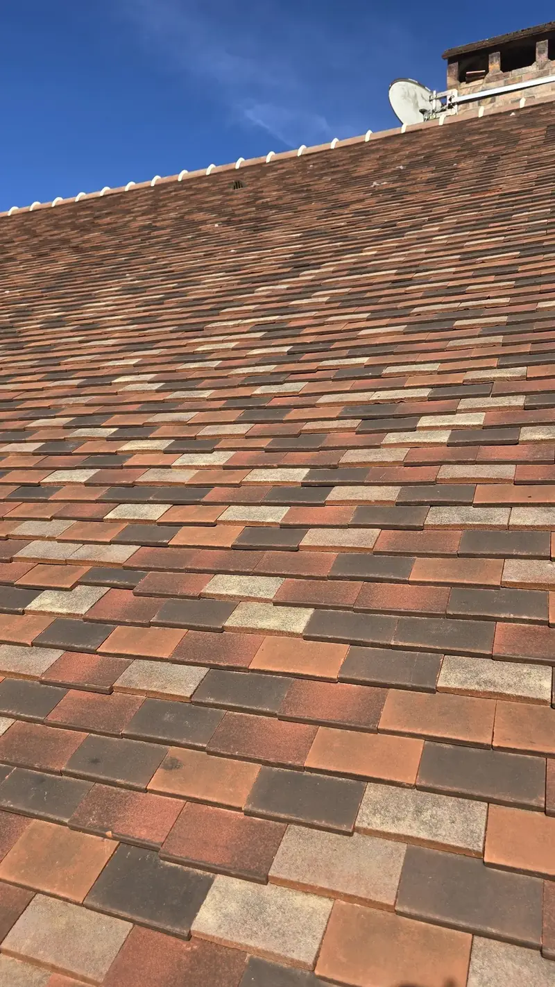 Gros plan sur des tuiles plates en terre cuite aux teintes panachées posées au pureau régulier, Chevreuse (78)
