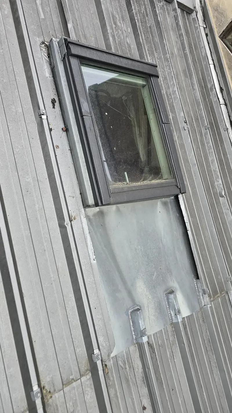 Fenêtre de toit sur une couverture en bac acier, raccord réparé avec une plaque rapportée, Choisy-le-Roi (94)