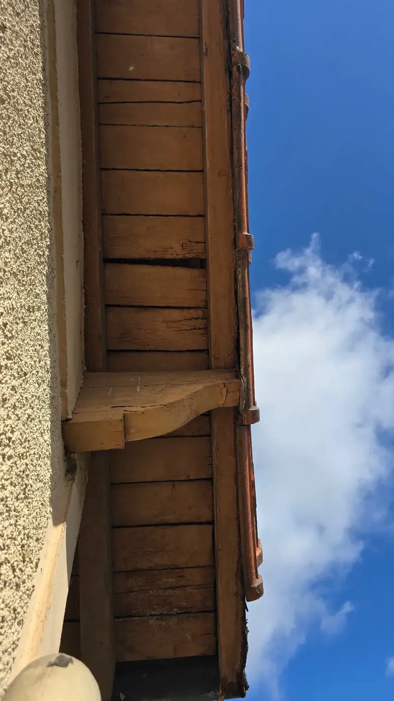 Sous-face bois avant reprise – Sous-face en planches de bois et console sous le débord de toit, abîmées, avant travaux
