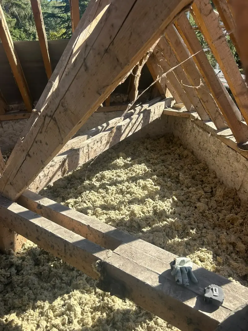 Isolation des combles perdus par soufflage de laine minérale entre les entraits de charpente