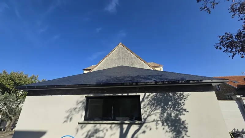 Croupe en ardoise, vue de face – Toiture à croupes en ardoise naturelle terminée, vue de face devant un ciel bleu