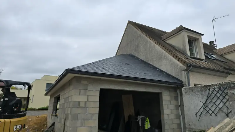 Gouttières posées – Extension en parpaings couverte d'ardoise naturelle avec gouttière posée, garage encore ouvert