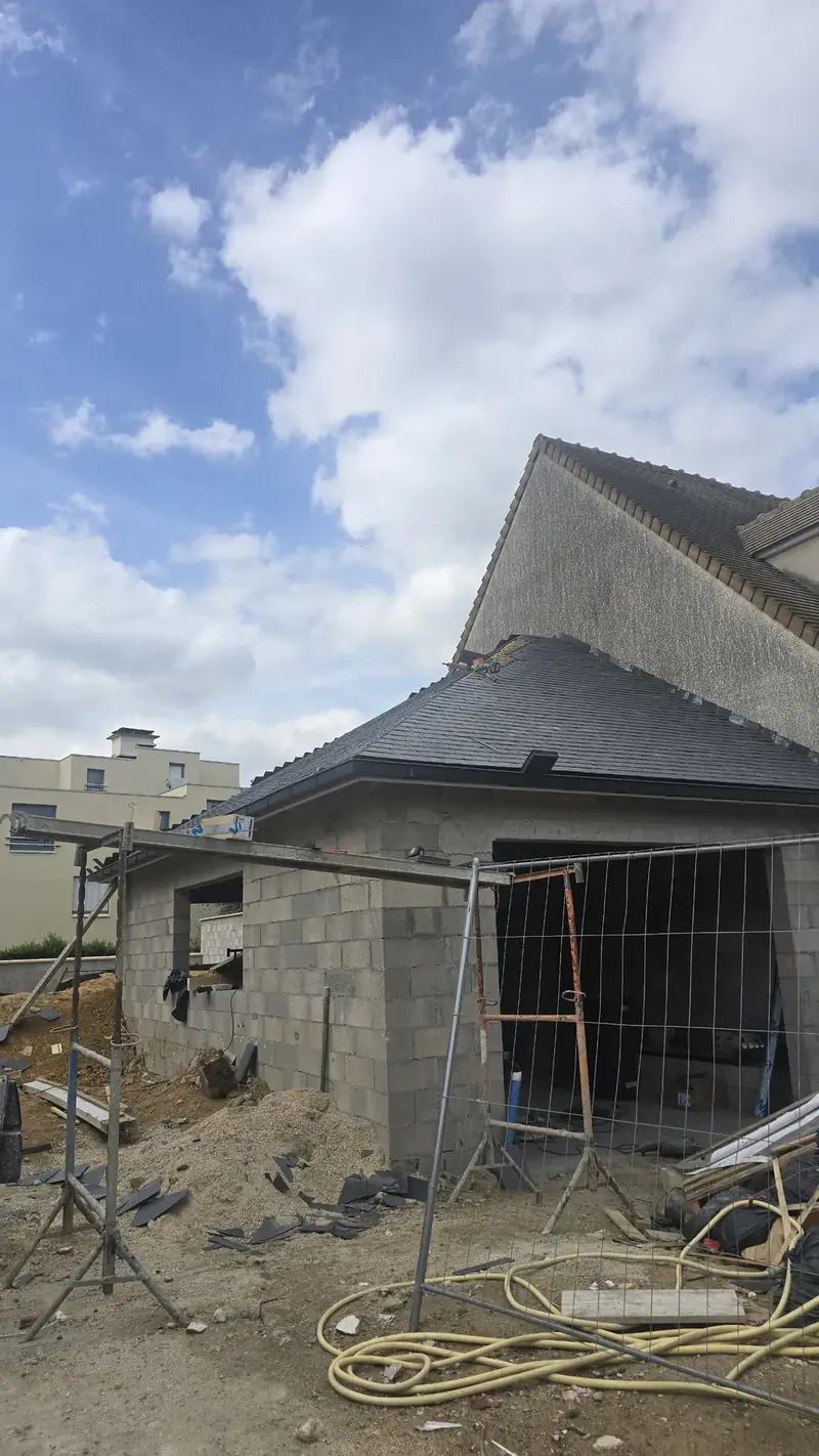 Pose de l'ardoise en cours – Toiture à croupes en ardoise naturelle presque terminée sur une extension en parpaings
